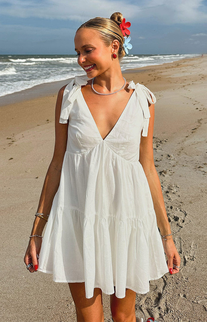 White mini dress with a deep V-neckline, tie-shoulder straps, and a tiered skirt design