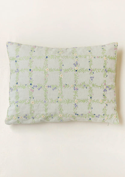 A light blue pillow with an embroidered floral grid pattern.