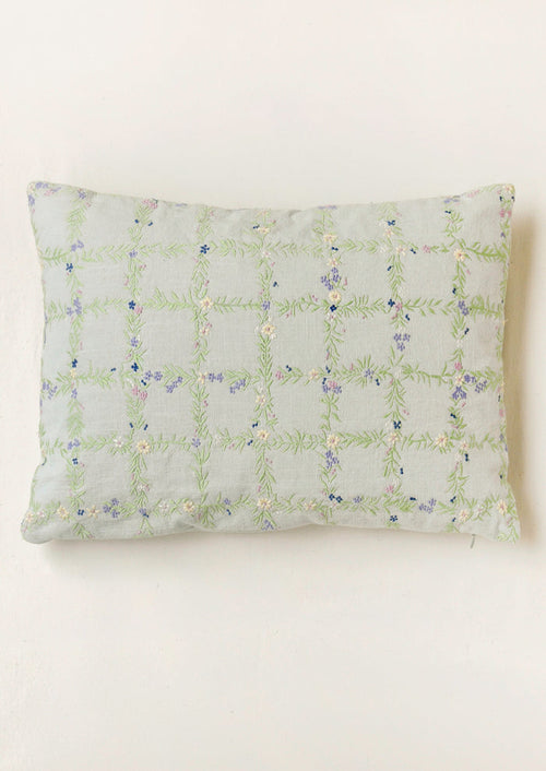 A light blue pillow with an embroidered floral grid pattern.