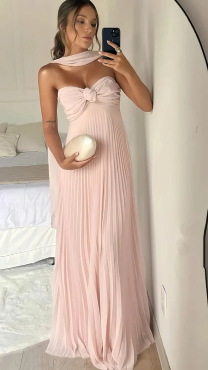 Woman wearing a pink strapless dress holding a white ball in a bedroom setting.