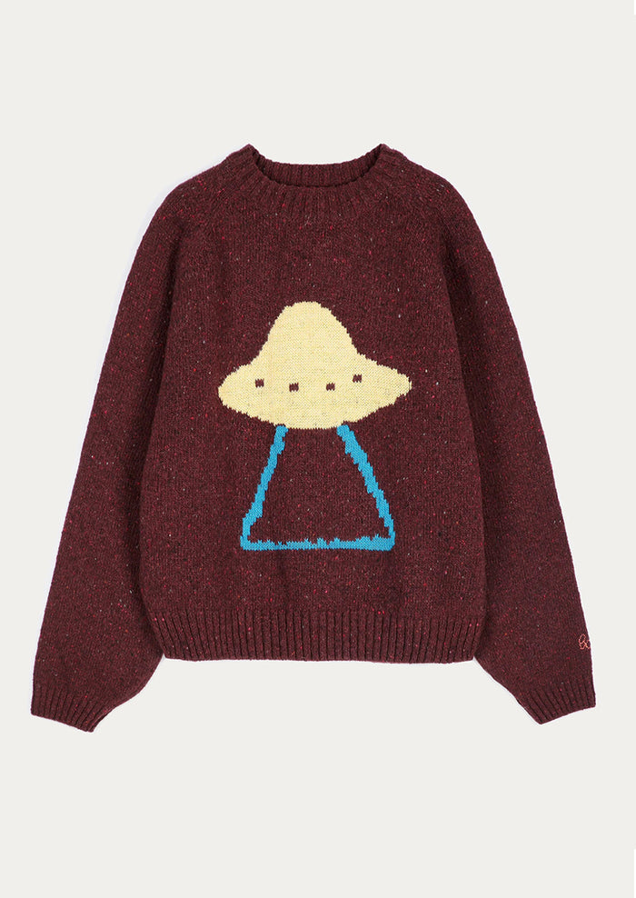 A dark burgundy knit sweater featuring a knitted graphic of a UFO with a beige dome-shaped head and blue legs, displayed against a light off-white background.