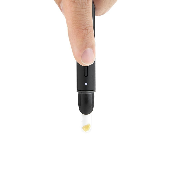 Puffco Hot Knife held by a finger, featuring a black body and a clear ceramic tip with a concentrate visible inside.